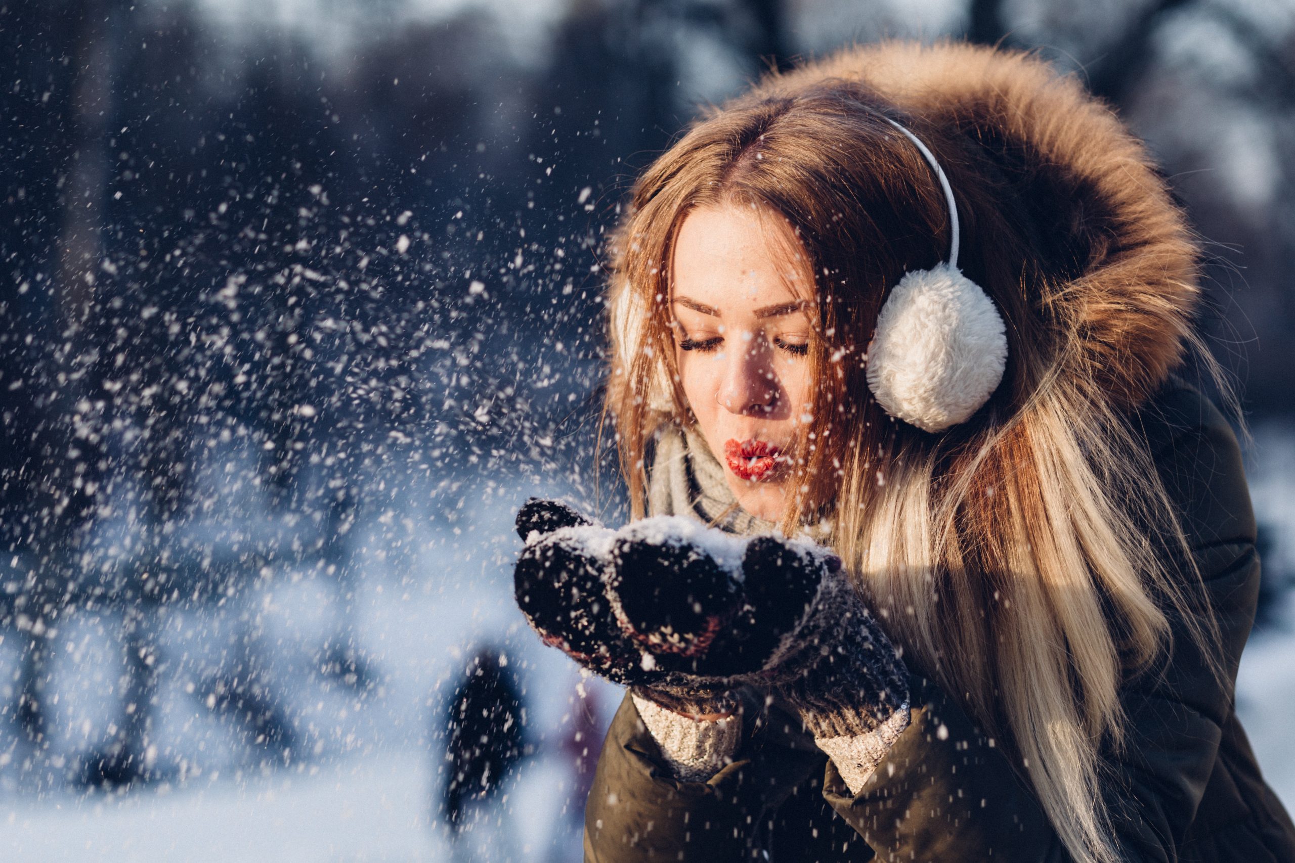 woman blowing snow on her hands